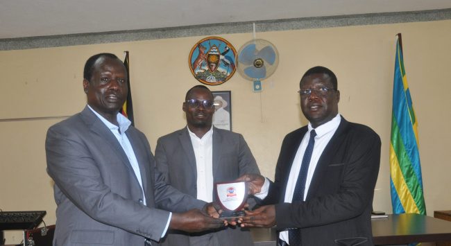 Commandant of NDC – U Maj Gen Francis Okello handing a Souvenir to Mr Okwalinga Alfred the Mayor of Gulu City as Mr Okwi Gilbert the Deputy RCC looks on at Gulu City Council Hall on 23rd June 22