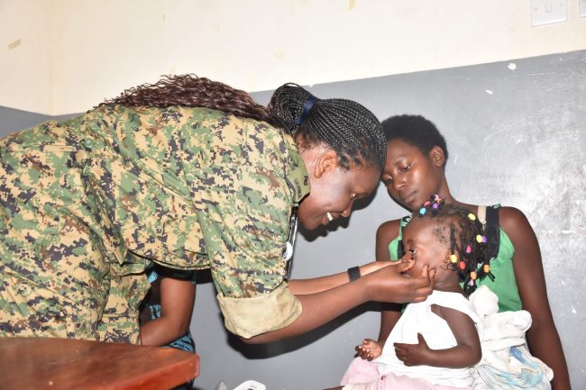 A UPDF clinician examining a child during a Health camp at Ishongororo Health Center IV