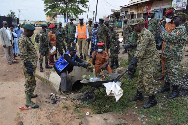 The mayor of Rushere town council King Martin Kyanyawanga loading rubbish onto a wheel barrow