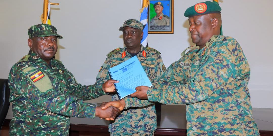 Brig Gen Chris Bagonza (centre) looks on as Col Joab Yebazibwe (right) hands over a report to Lt Col Yona Tumuvamye (left) during a handover ceremony at the Land Force Headquarters in Bombo..jpg