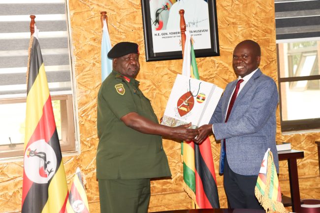 Lt Gen Sam Okiding (R) handing gift to Brig Gen Maxwell Masuku from Zimbabwe Defence Forces at MoDVA hq
