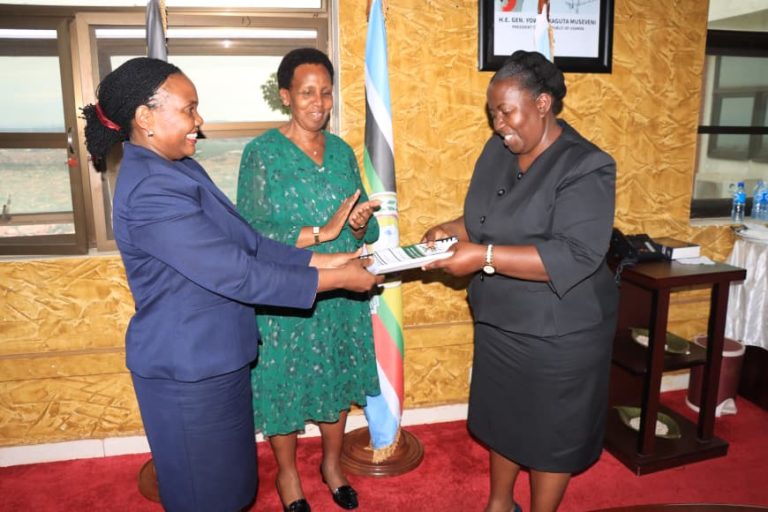 Ms Harriet Kyomugisha (L) handing over instruments of office to Ms Bamwonjobora Celia as Presiding officer Ms Edith Buturo looks on.JPG